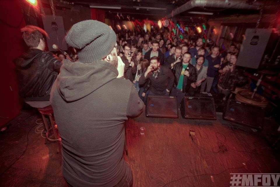 Artist Tommy Dillon faces a crowd of fans from the stage at Sneaky Dees