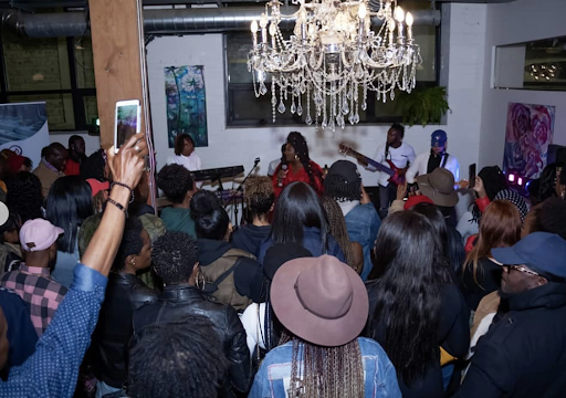 A crowd surrounds Toronto artist Tracey Kayy performing at the Centre for Social Innovation