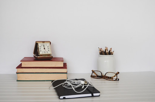 a pair of glasses, a plant and some books on a white desk