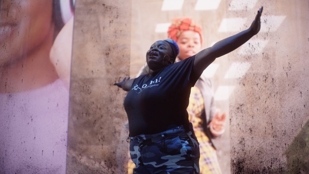 a woman stands tall with her arms stretched out while smiling in front of an image of a young girl