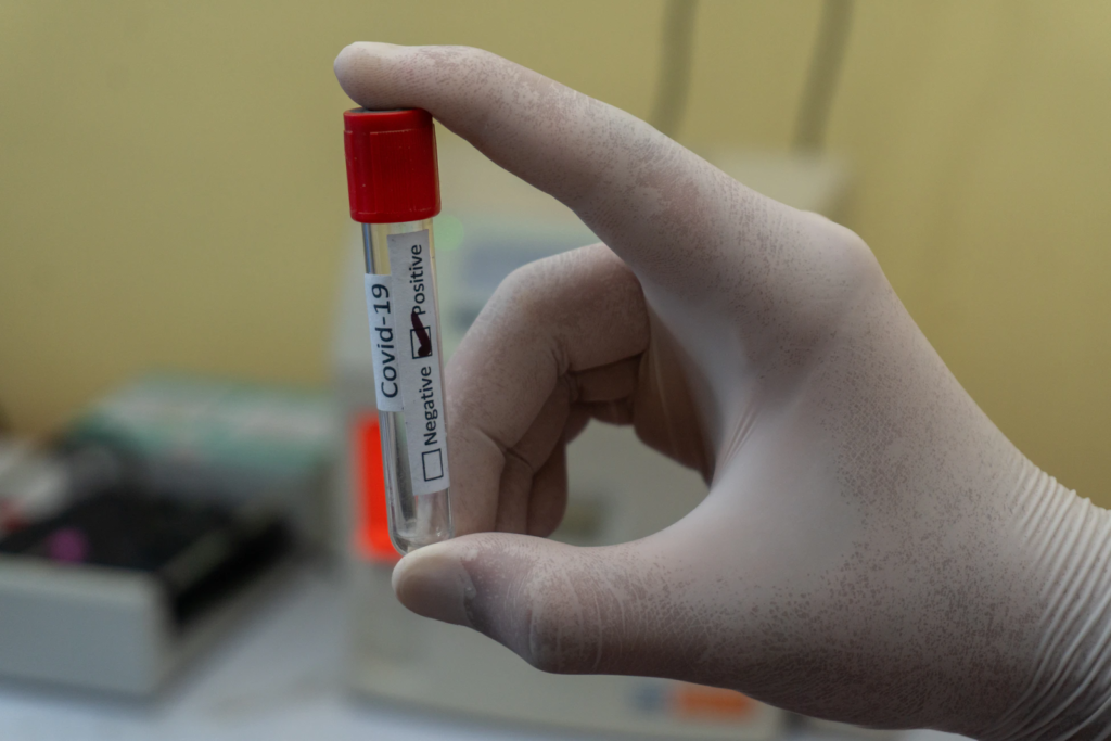 a white gloved hand holds an empty vial in between their thumb and index finger