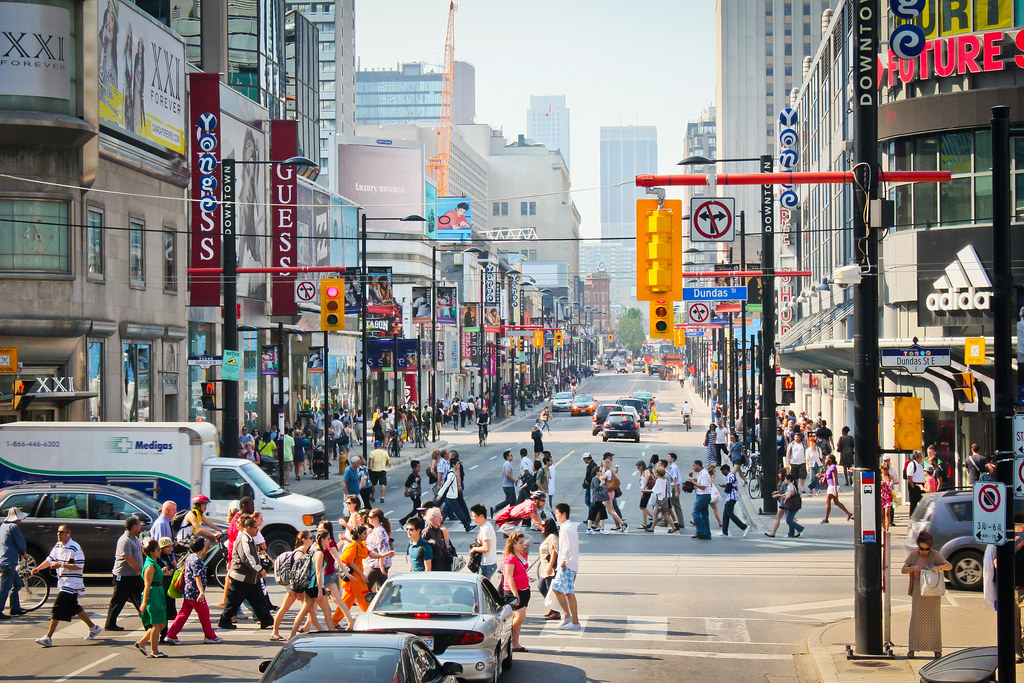 a busy intersection with cars and pedestrians roaming the streets