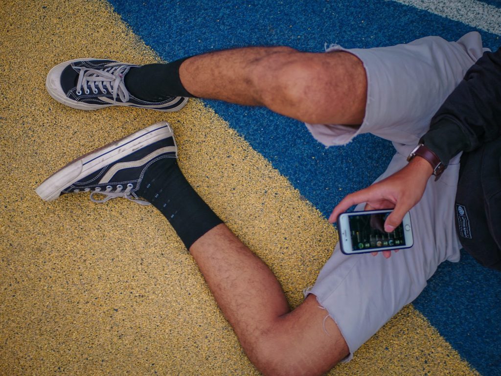 a shot of a man's hairy legs sprawled across the floor with a phone in his hand