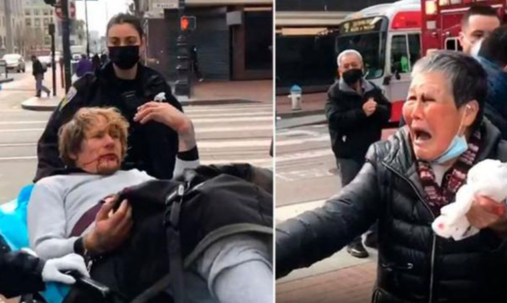 a white man lays in a stretchy with a bloody face and an elderly asian woman on the right yells at him for attacking her out of nowhere who also has blood on her face
