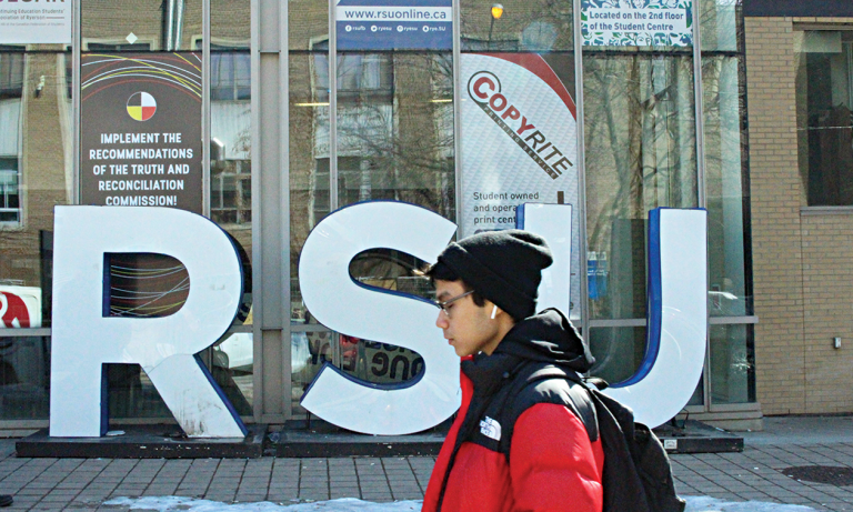 Photo of a student walking by the RSU sign on Gould St.