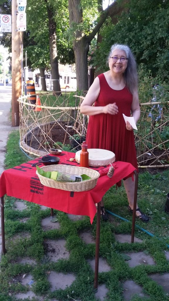 a woman in a red dress stands on some grass with a table with baskets on top