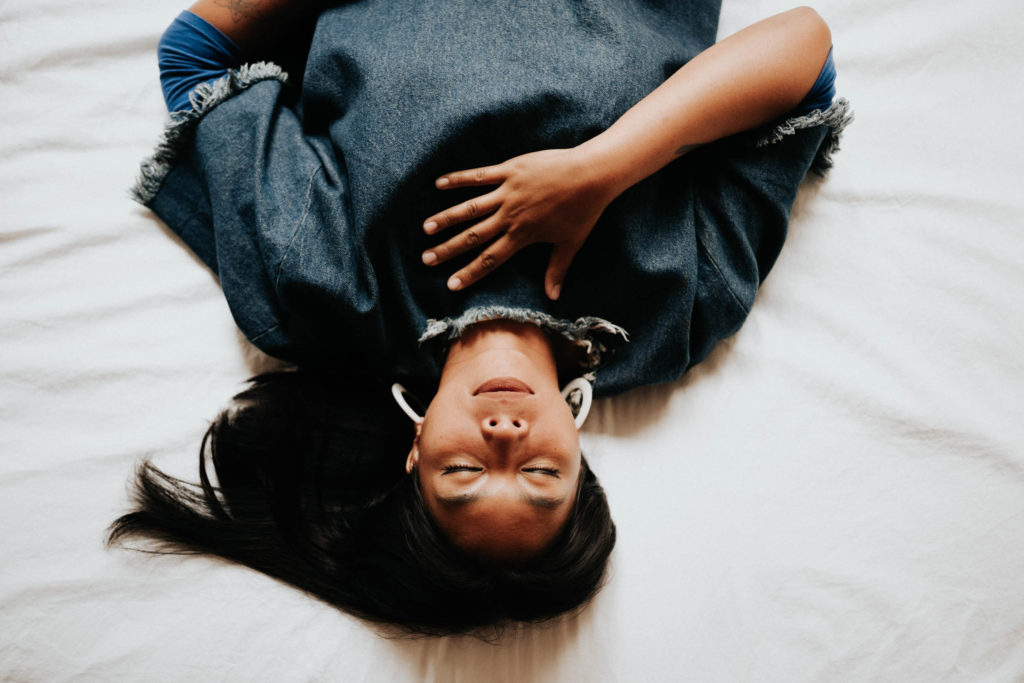 a woman is upside down on a bed with her eyes closed