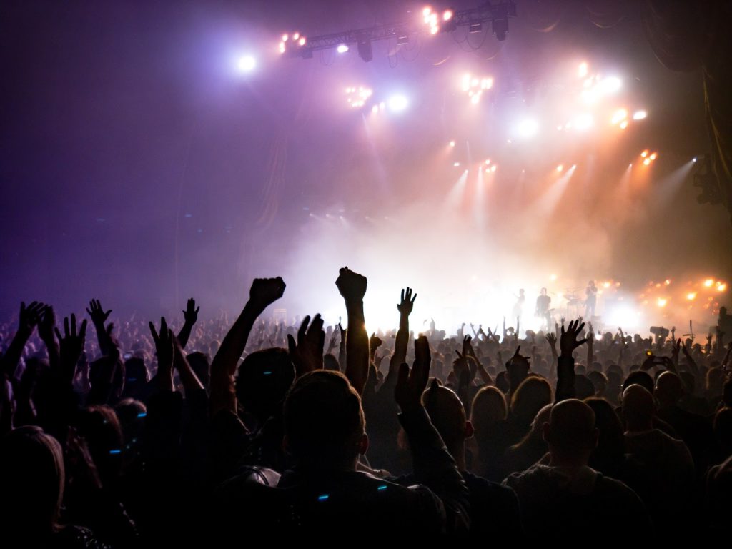 a silhouette of a huge crowd at a concert with their hands up