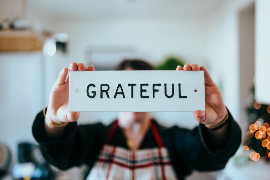 a person holds a sign that says grateful in front of their face to the camera