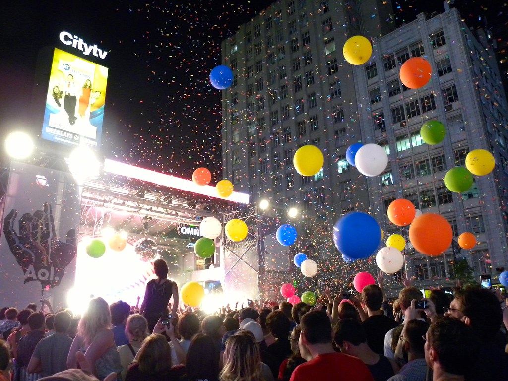 a crowd of people are at a concert at night time with balloons flying around in the air