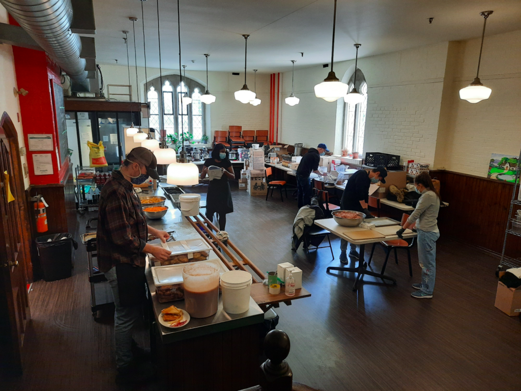 workers wear masks and make food in a kitchen