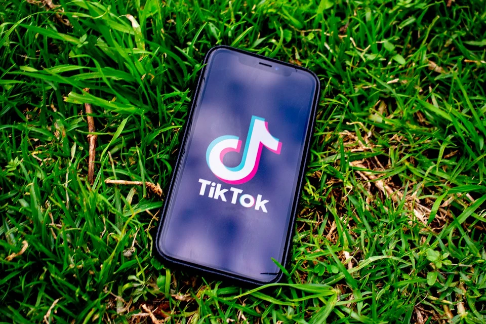 an iphone on some grass with the tiktok app open on it