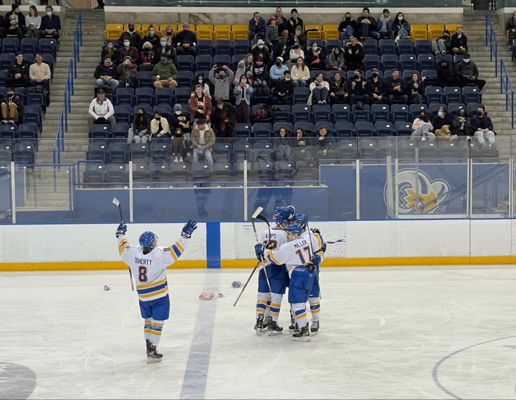 Photo of hockey players hugging on the ice in an arena.