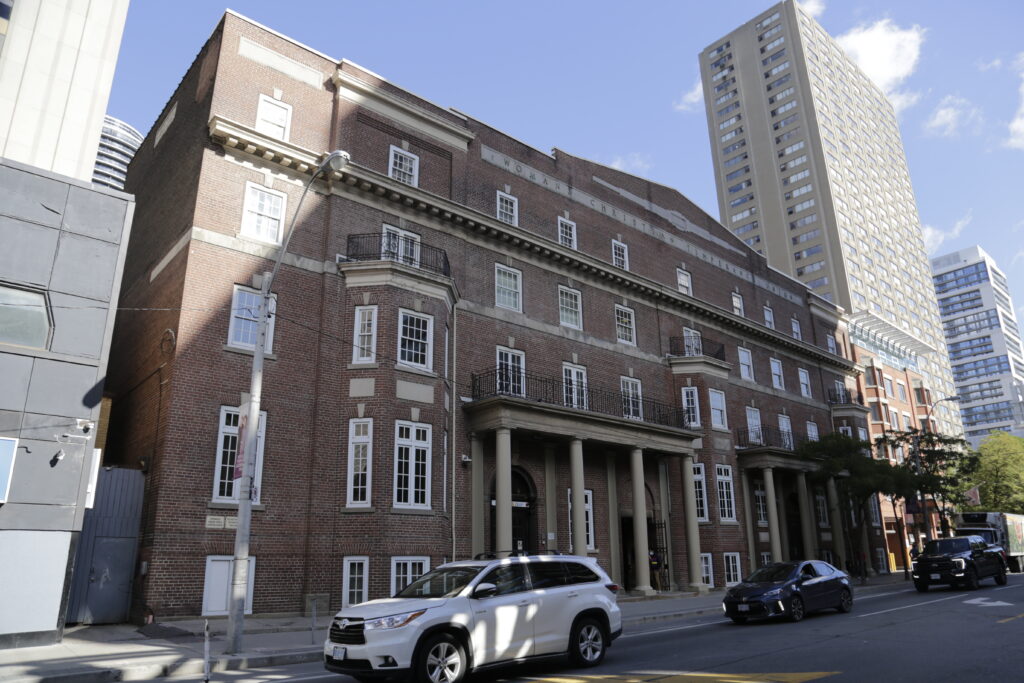 Cars drive in front of Covenant house on Gerrard St in Toronto.