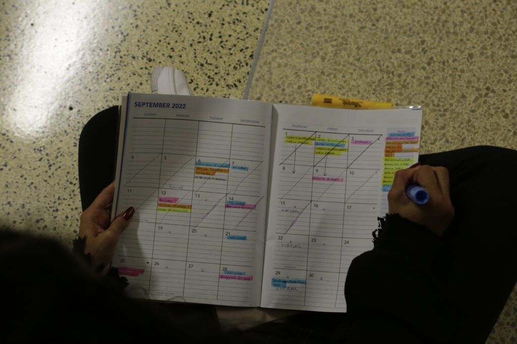Maliha Hemani posing for a photo with her highlighters and planner.