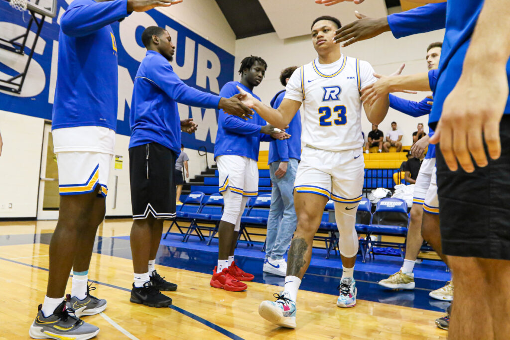 A basketball player high fives his teammates as he walks onto the court.