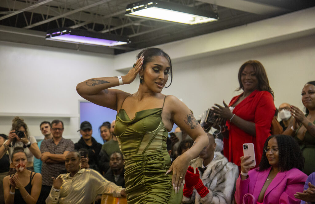 A woman in a green dress posing at the end of a runway.