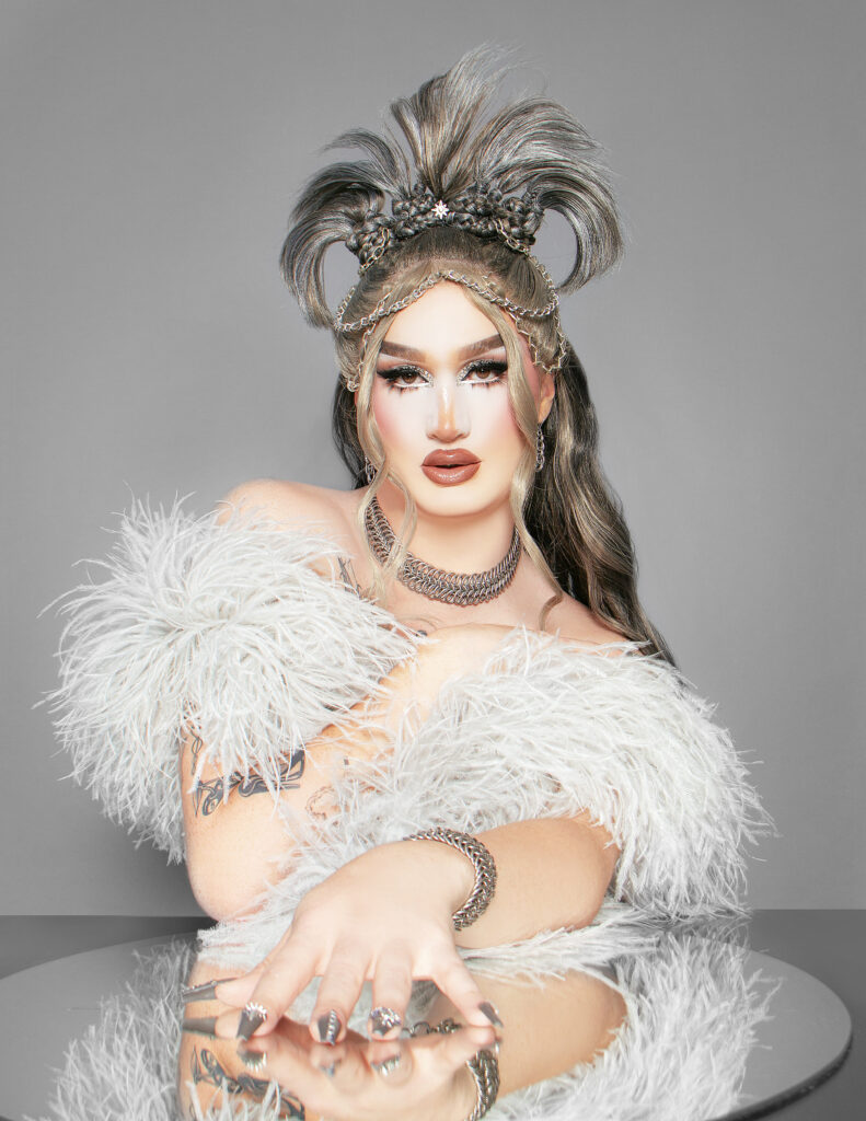 Woman with pearls and silver hair in front of a grey background