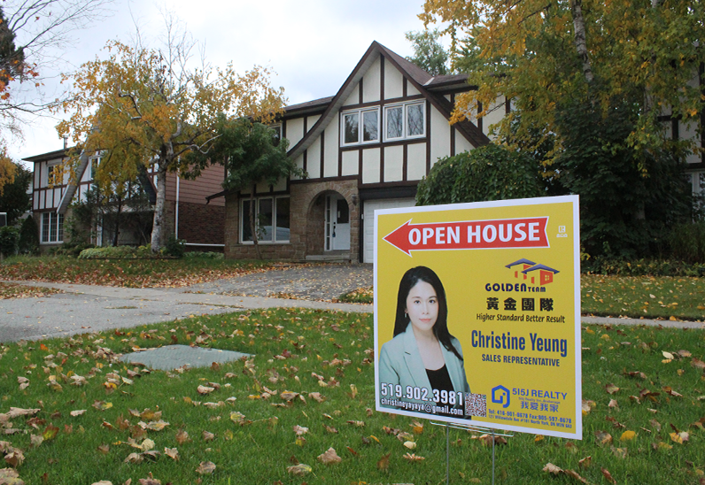 Image of a home with an open house sign on the lawn.