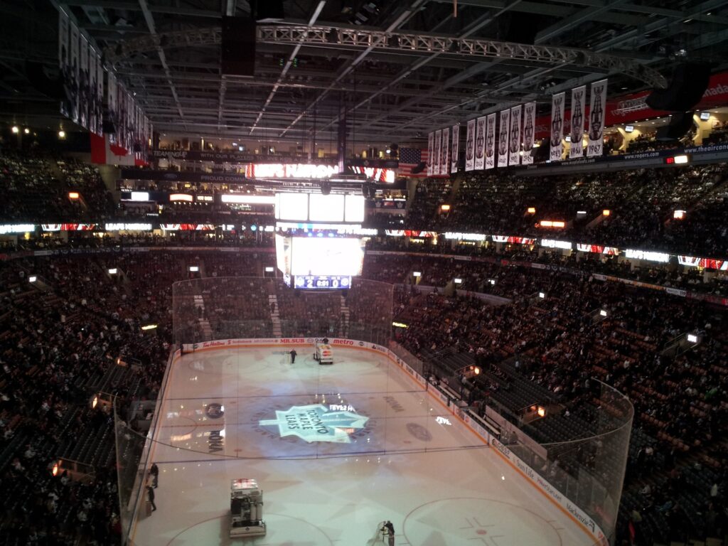A photo from the stands looking down at a hockey arena displaying a lighted Toronto Maple Leafs logo.