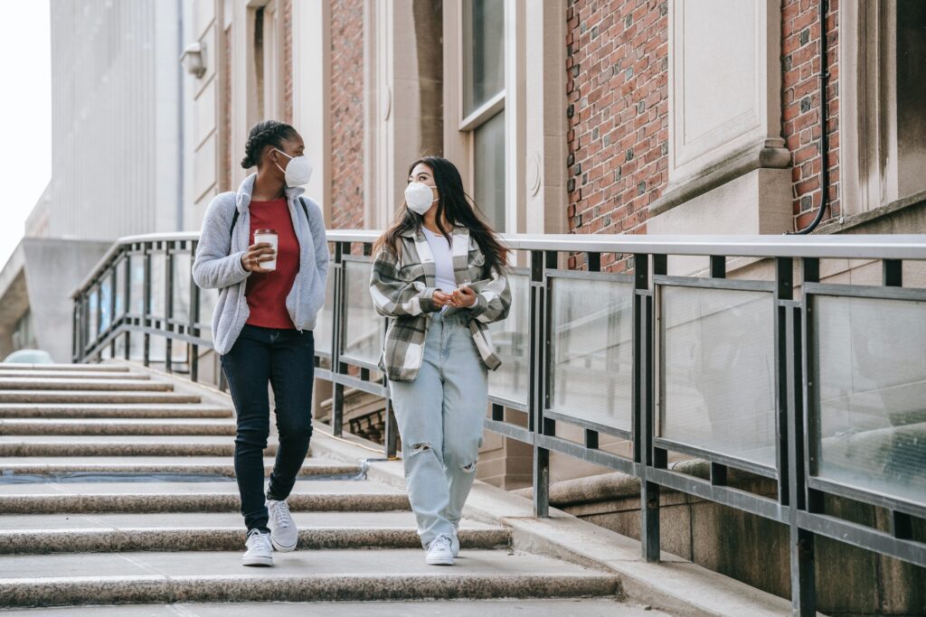 Two people with masks on walking down stairs.