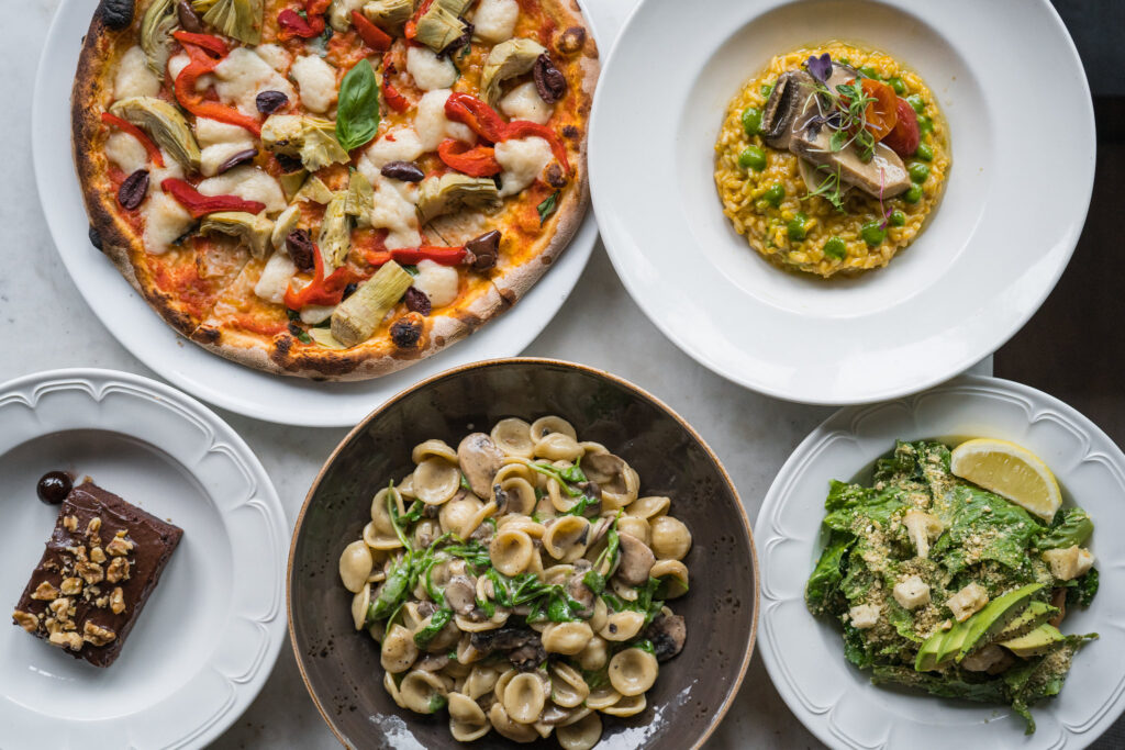 A picture of a variety of meals, including a pizza, chocolate dessert and a salad.