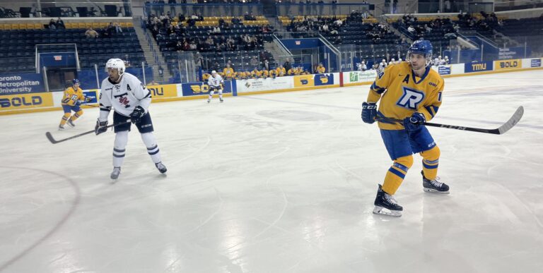A hockey player waits for a pass, as an opposing player looks on nearby.