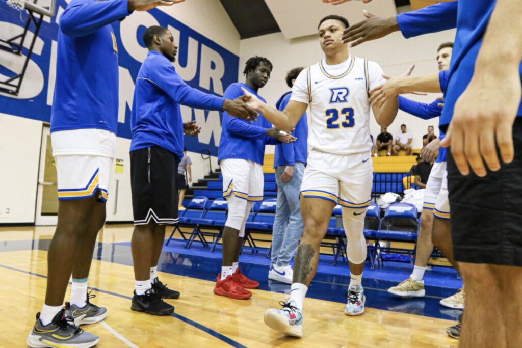 A basketball player high fives his teammates, as he walks onto the court.