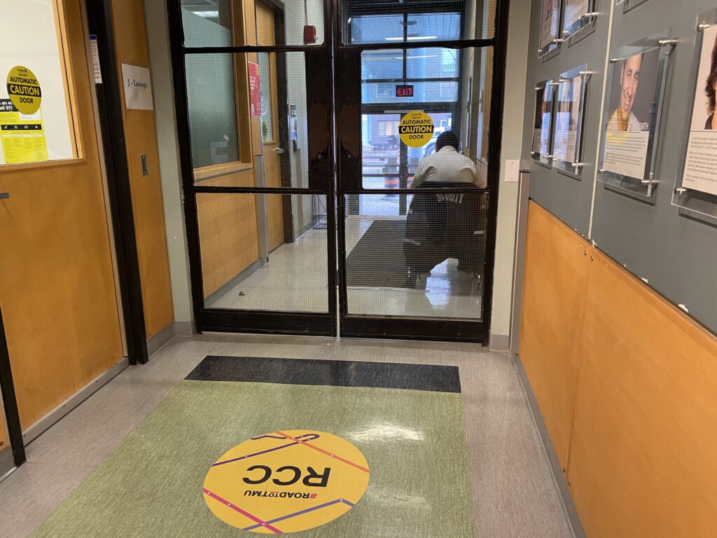 A security guard sits in the hallway of the Roger Communications Centre with his back turned to the camera.