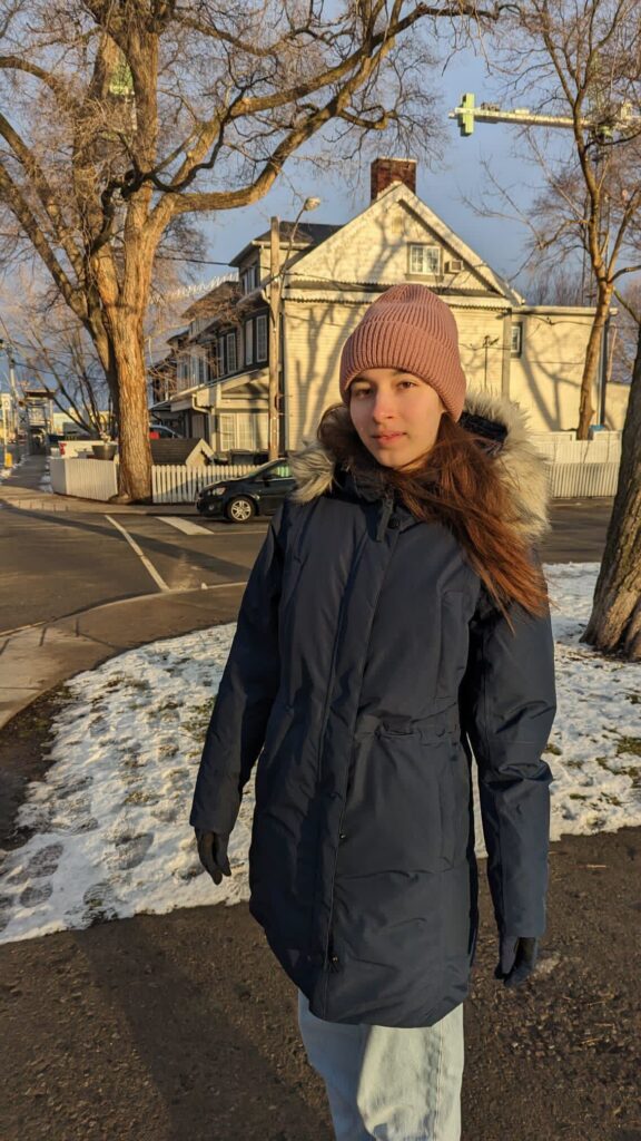 A girl smiling on the camera during a cold winter.