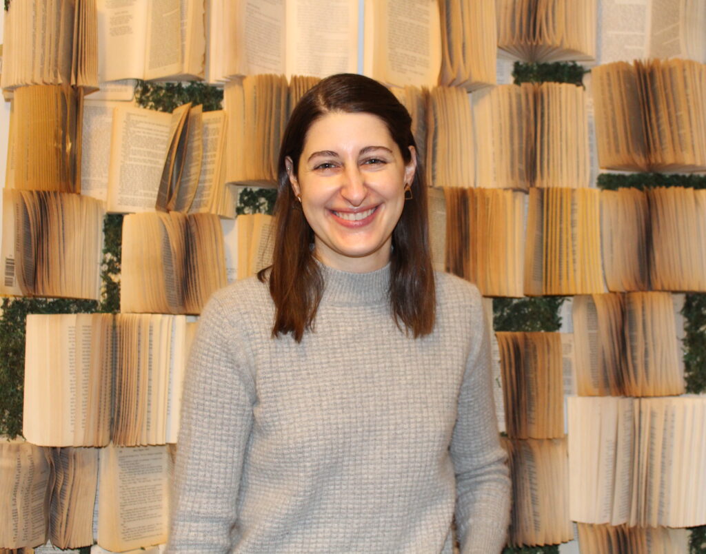 Julianna Notten standing in front of a book wall she built. (Kadija Osman/On The Record)