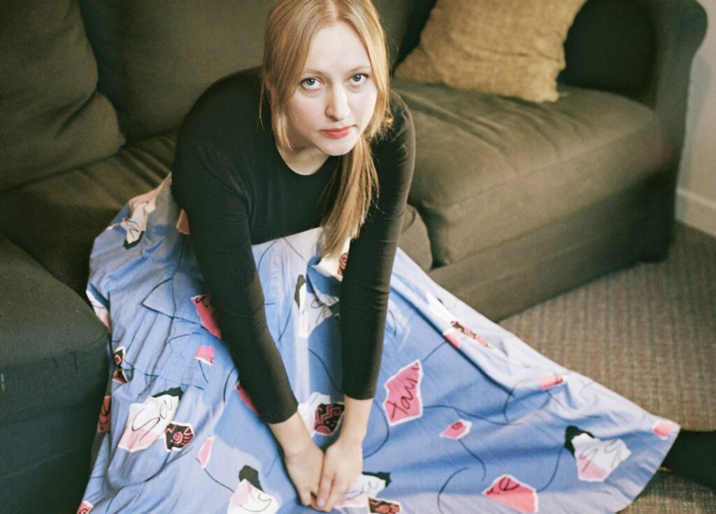 Eliza Niemi sitting on a couch with her legs stretched out.