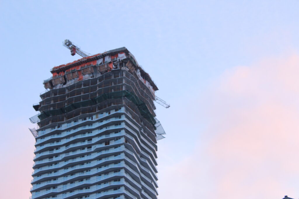 A highrise building in Toronto where the bottom half is finishing and the top half is still under construction.