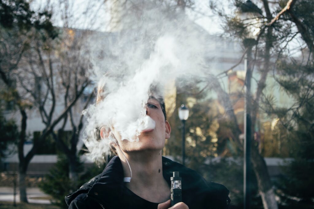 Photo of a man using a vape pen.