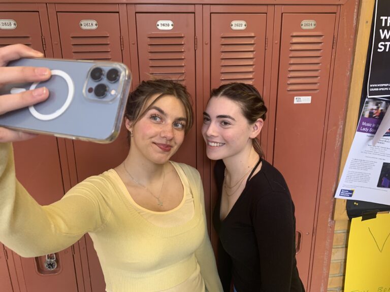 two friends taking selfie in front of lockers