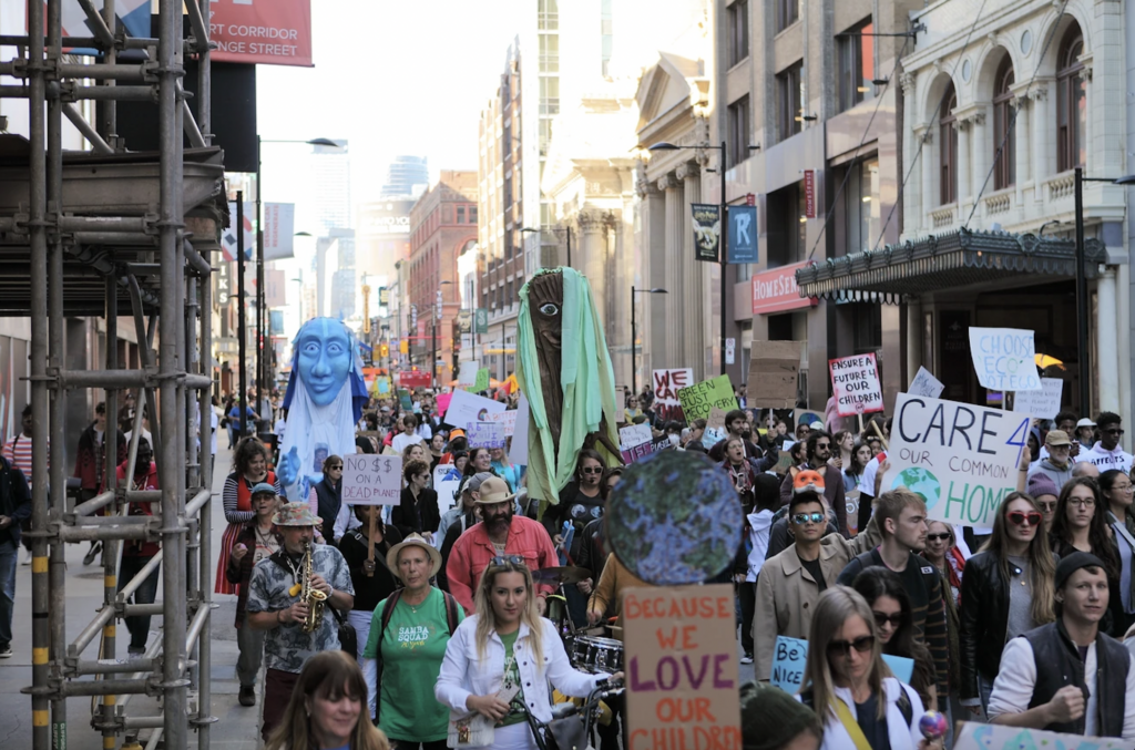 Street full of people marching with signs protesting climate change.