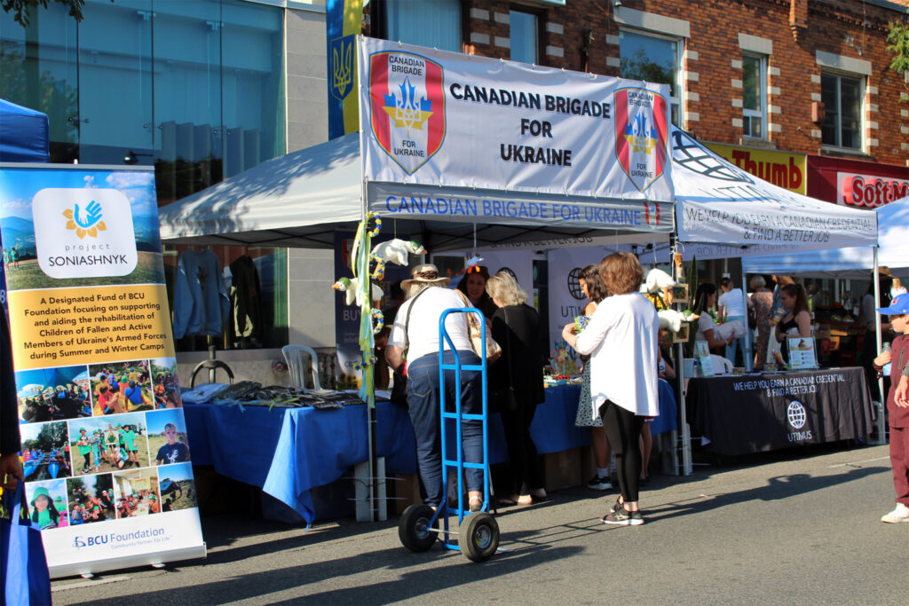 A tent vendor on the street surrounded by people who are inquiring about flyers.