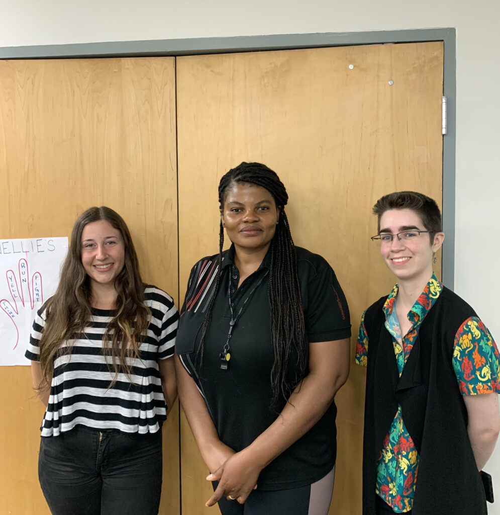 Workshop staff Rowan Goldman, Sam DeFranco and Peace Onyia stand together smiling. 