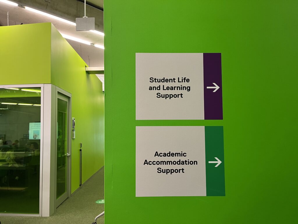Green wall with sings pointing to Academic Accommodation Support and Student Life and Learning