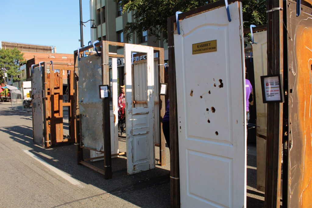 Bullet riddled doors are displayed on the street. 