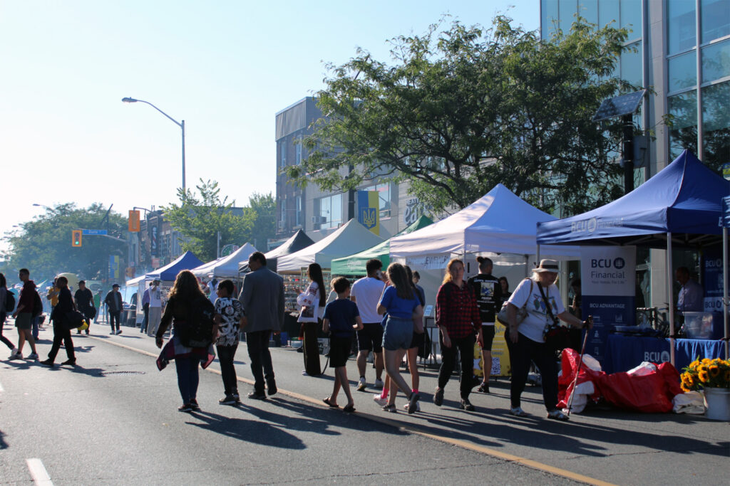 Crowds of people walk up and down on Bloor St. Vendors and tents line up the block selling Ukrainian goods. 