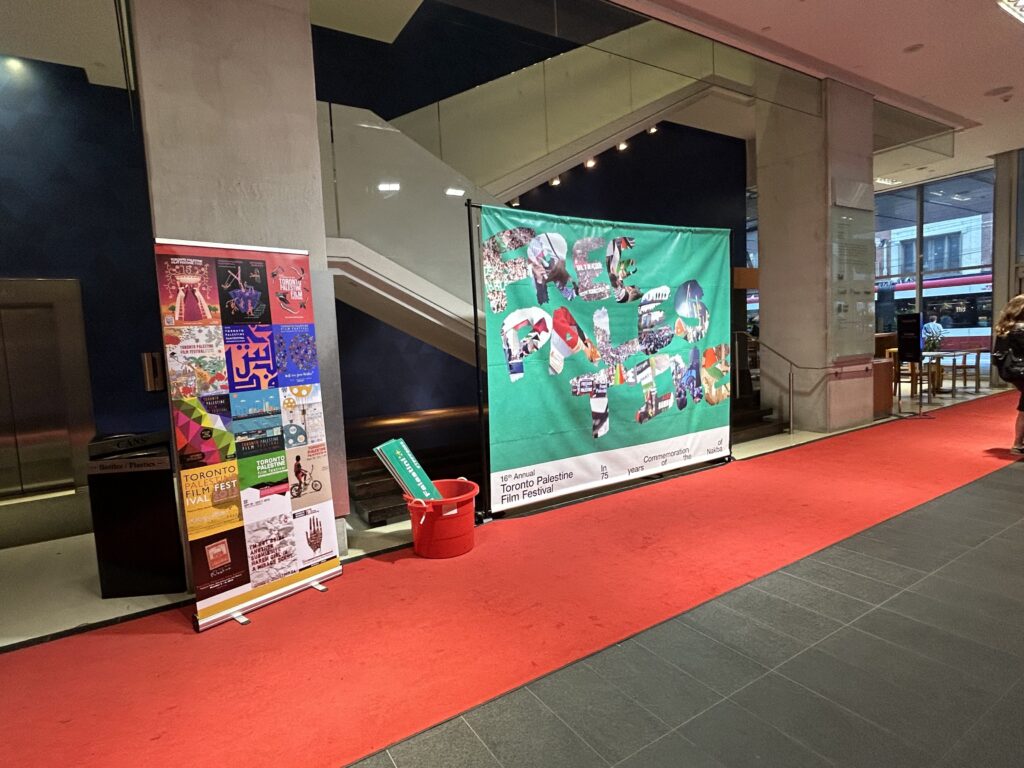 (from left to right) red carpet rolled out for the event, along with two promotional posters, one saying "FREE PALESTINE", another promotional poster on the red carpet with a mosaic of graphics, each with the words "Toronto Palestine Film Festival"