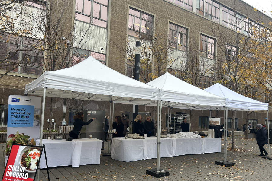 Three white tents are set up outside on Gould Street, where on tables are servings of chili.