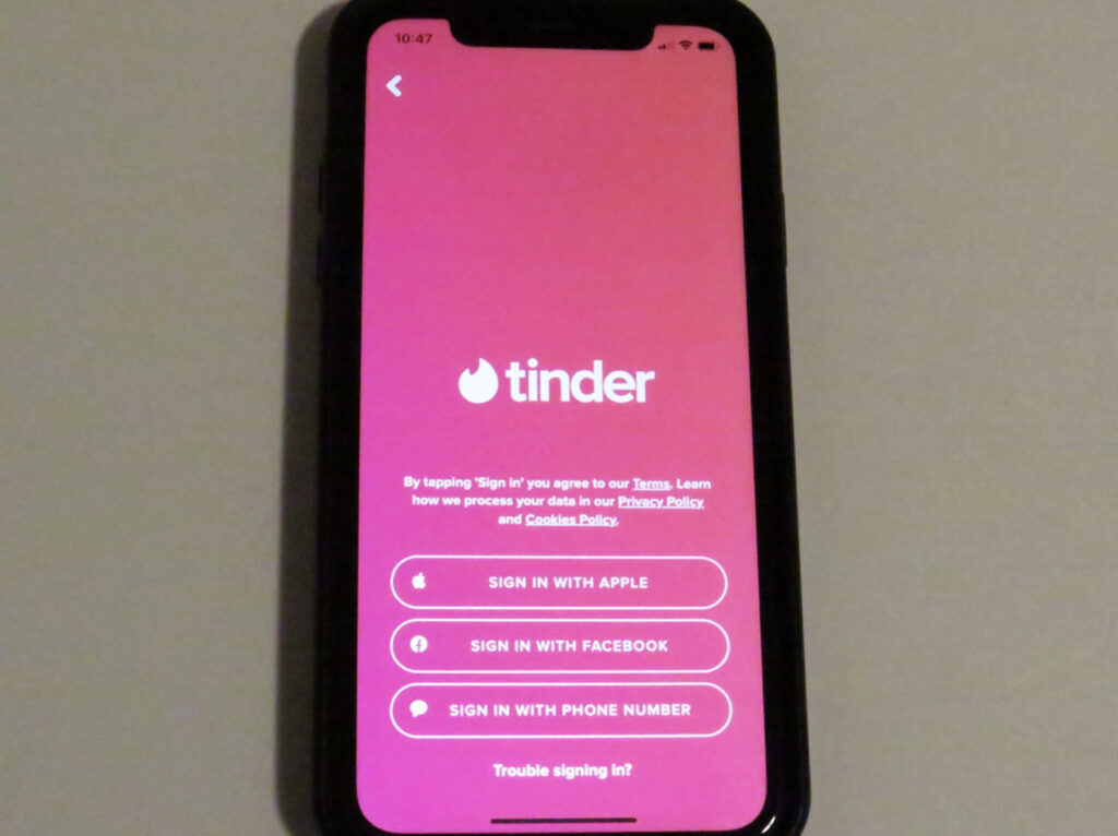 A phone showcasing the login page of the Tinder app, which says to sign in.