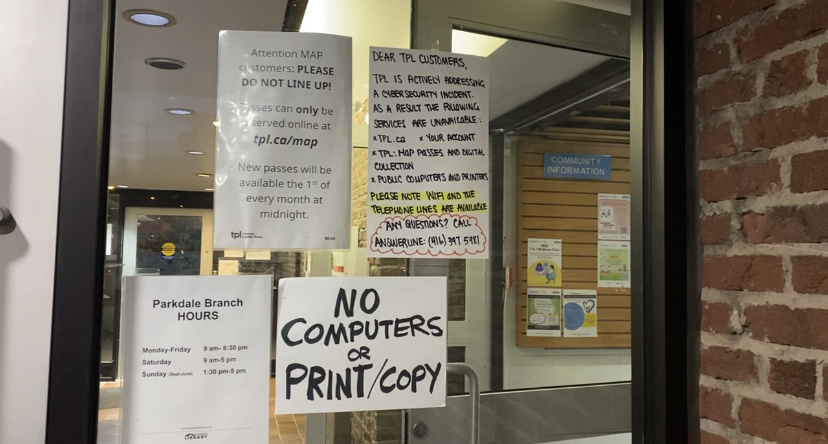 Several notes are taped to the door of the Toronto Public Library Parkdale branch. The notes read "Dear TPL Customers, TPL is actively addressing a cybersecurity incident. As a result, the following services are unavailable: tpl.ca, your account =, tpl map passes and digital collection, public computers and printers. Please note Wifi and telephone lines are available. Any questions? Call Answerline 416-397-5981