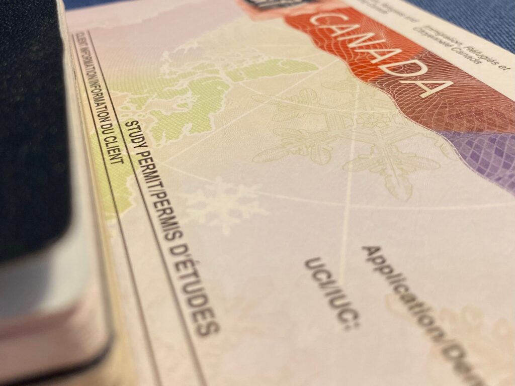 Image shows a passport on top of an international student's study permit