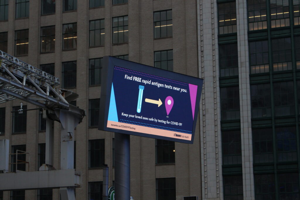 Screen showing an advertisement for free rapid antigen tests at Yonge-Dundas Square