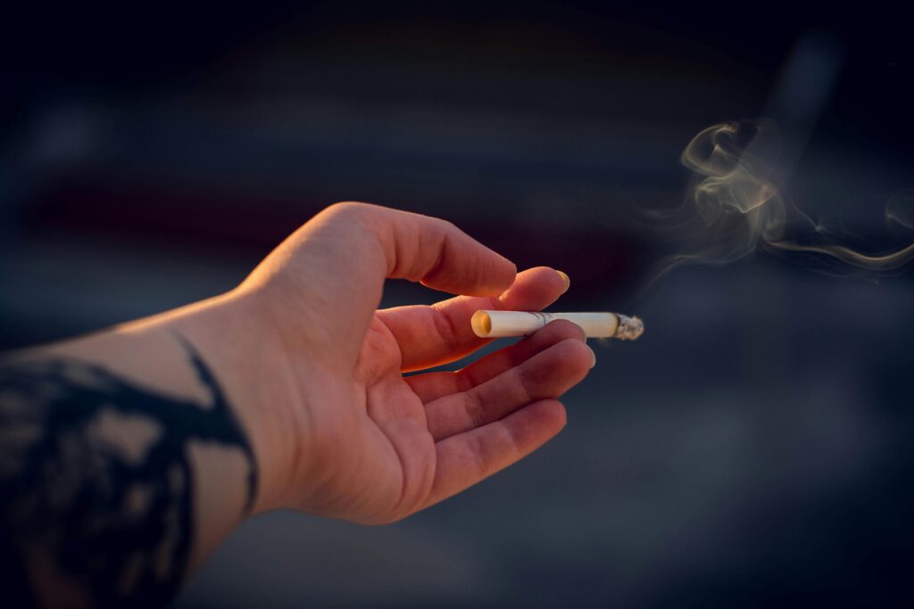 A hand holding a burning cigarette.