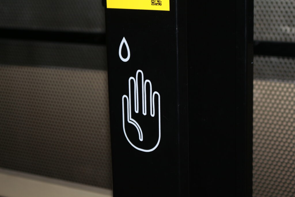 White hand graphic on black hand sanitizer stand