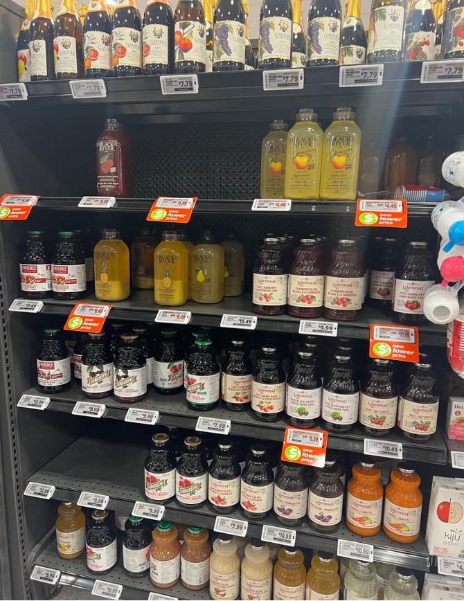 Different bottles of juice on a grocery store shelf.